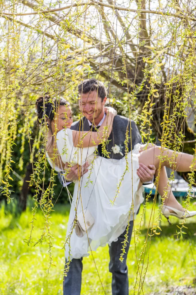 Jeune couple souriant échangeant des voeux lors d'une cérémonie de mariage en plein air, décorée de fleurs blanches et de guirlandes lumineuses