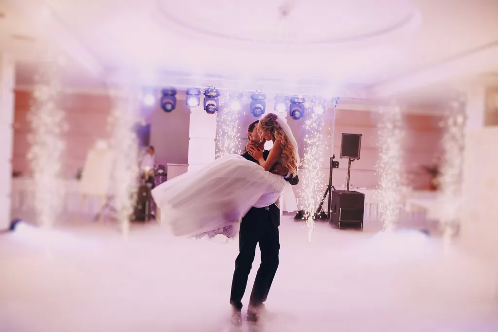 Jeune couple dansant passionnément lors de leur réception de mariage, entourés d'invités et sous des lumières scintillantes