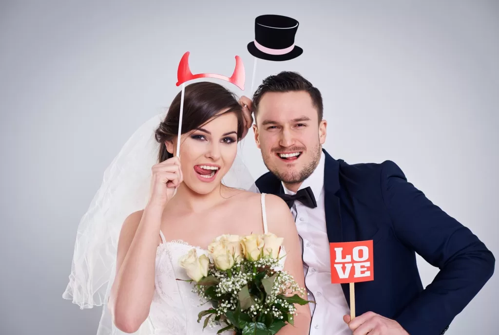 Couple de mariés s'amusant dans un photomaton déguisé lors de leur mariage