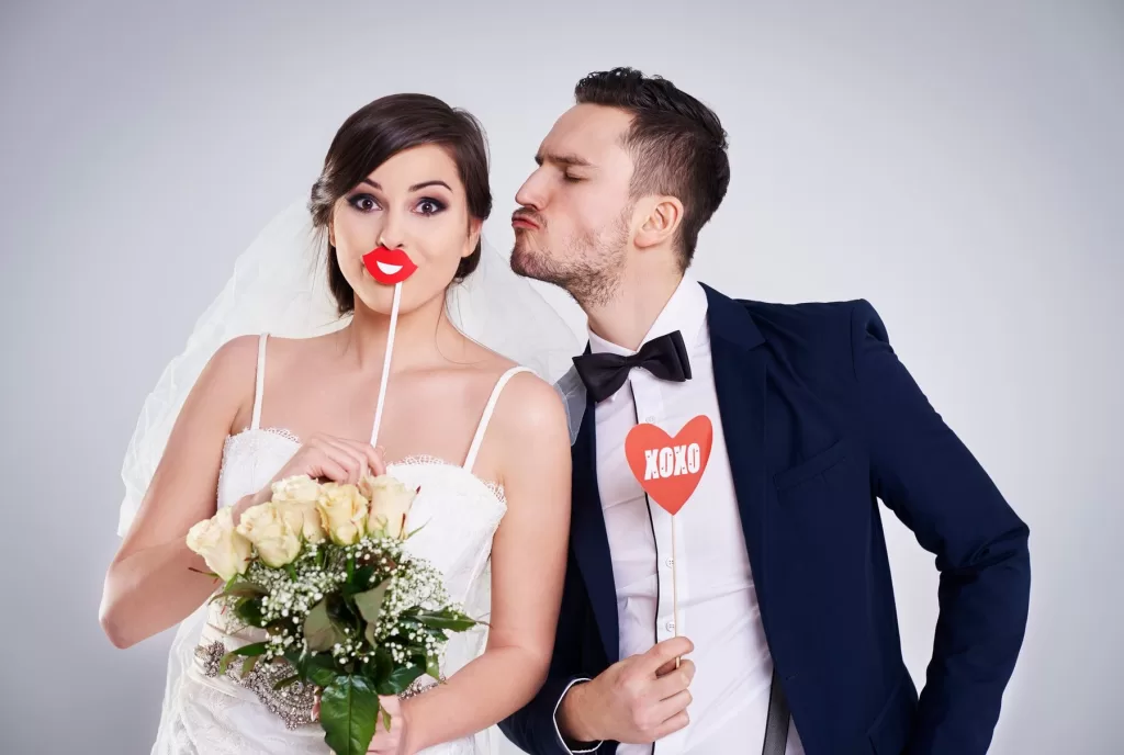 Couple de mariés s'amusant dans un photomaton déguisé lors de leur mariage